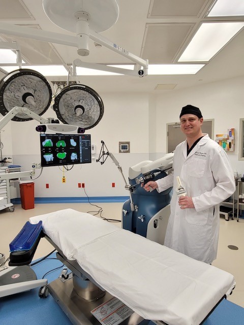 Dr Timothy Hawkes standing in operating room with the Mako SmartRobotics